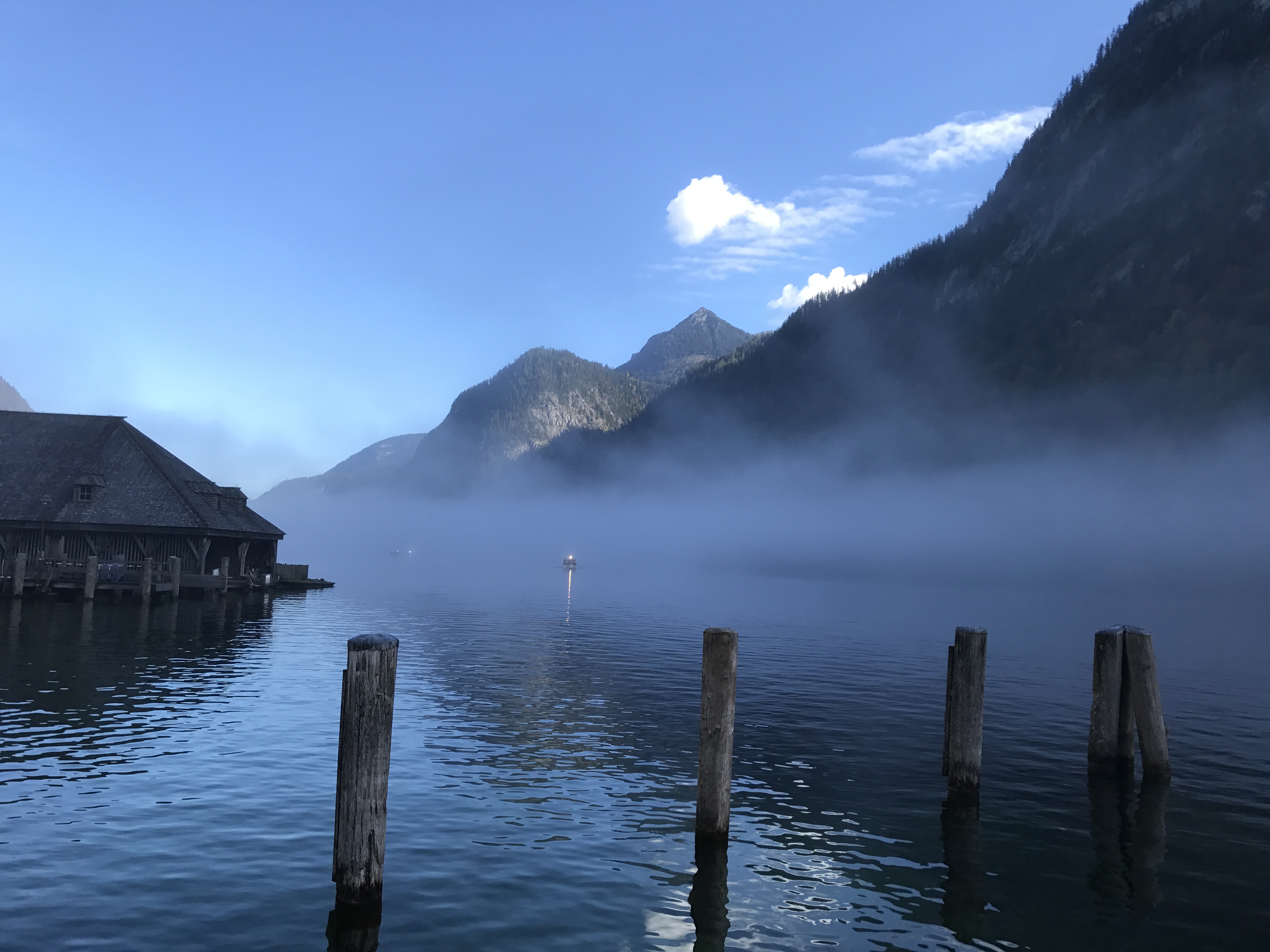 Ein Bergsee im Tal, umgeben von einer Berglandschaft. Der See ist nebelumwogen.